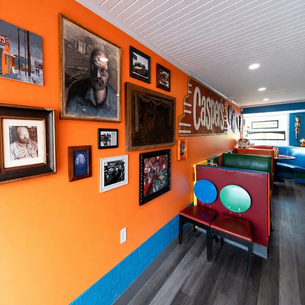 Casper's restaurant interior with orange walls, framed art, and colorful booths and chairs.
