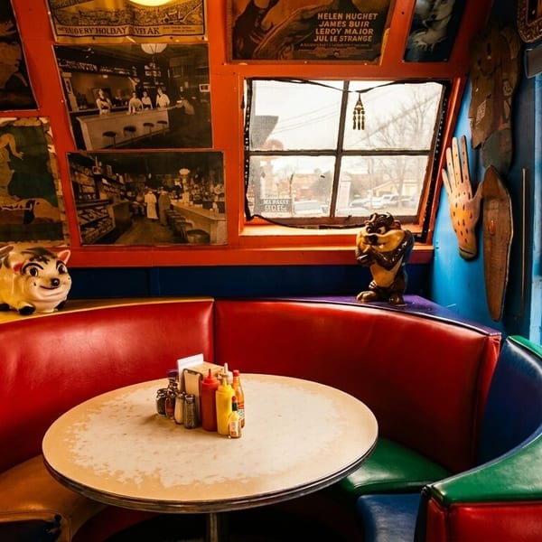 A colorful diner booth with red and blue seating, a round table, and vintage decor.